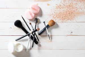 Sminkborstar och puder på ett vitt brädgolv