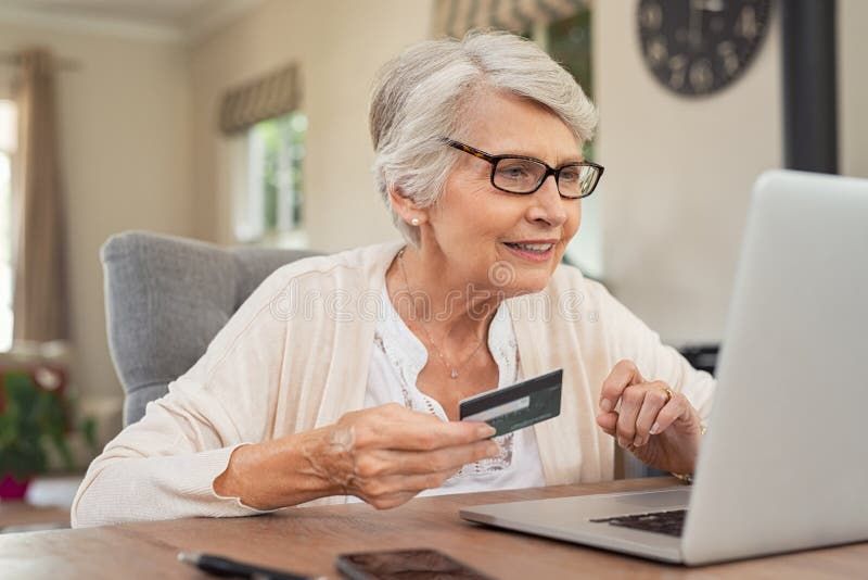 En glad kvinna 55+ handlar online med betalkort och laptop.