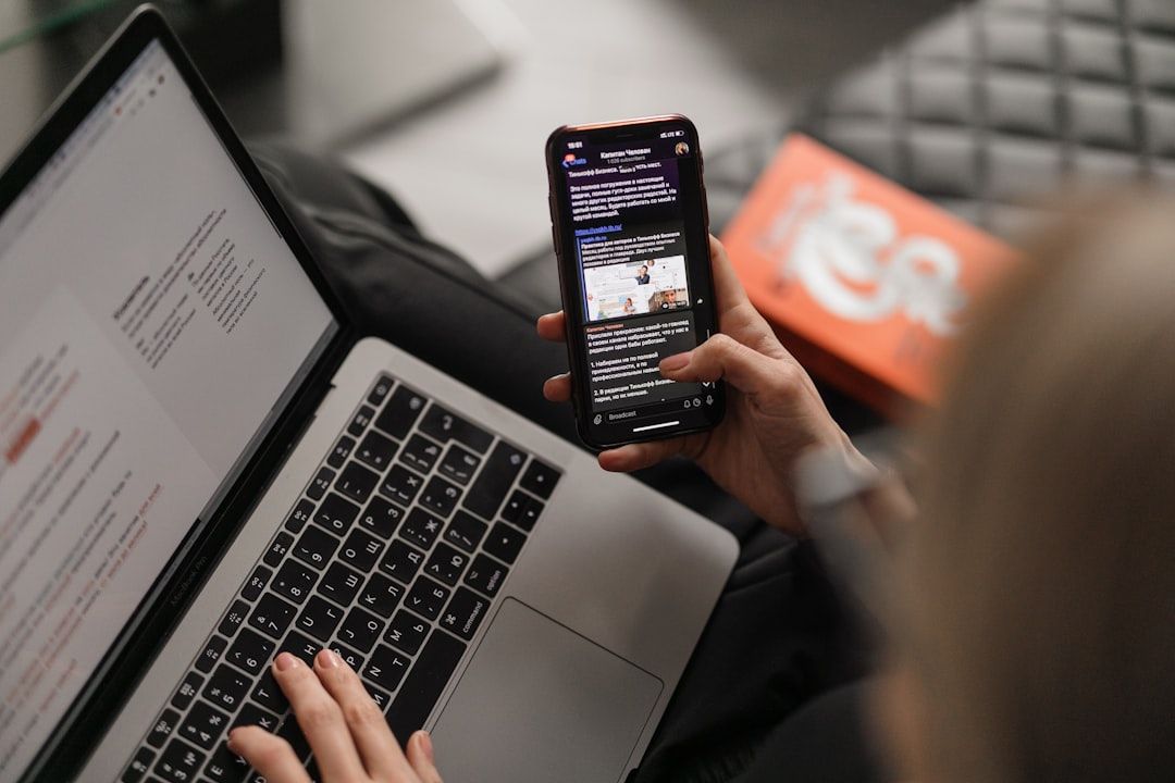En person som läser ett digitalt nyhetsbrev i mobilen vid sin laptop.