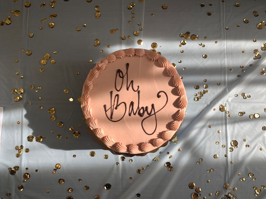 Rosa gender reveal-tårta med texten Oh Baby på ett glittrigt bord